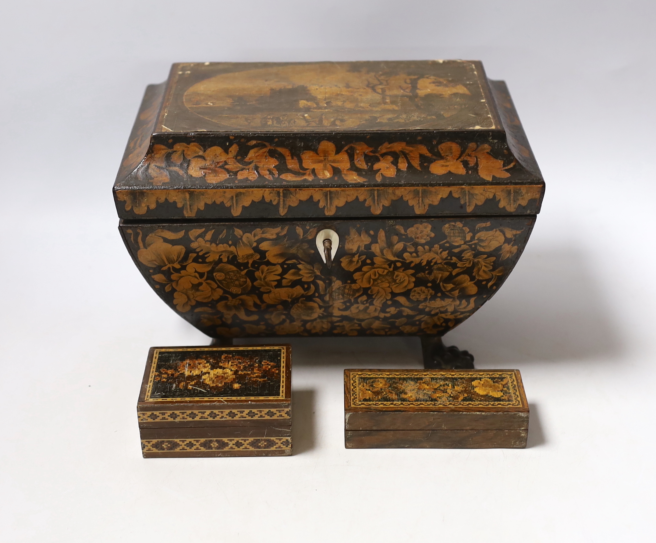A Regency penwork tea caddy, the cover inset with an engraving of figures by a castle, 23.5 x 16 x 16cm and two small Tunbridge ware boxes